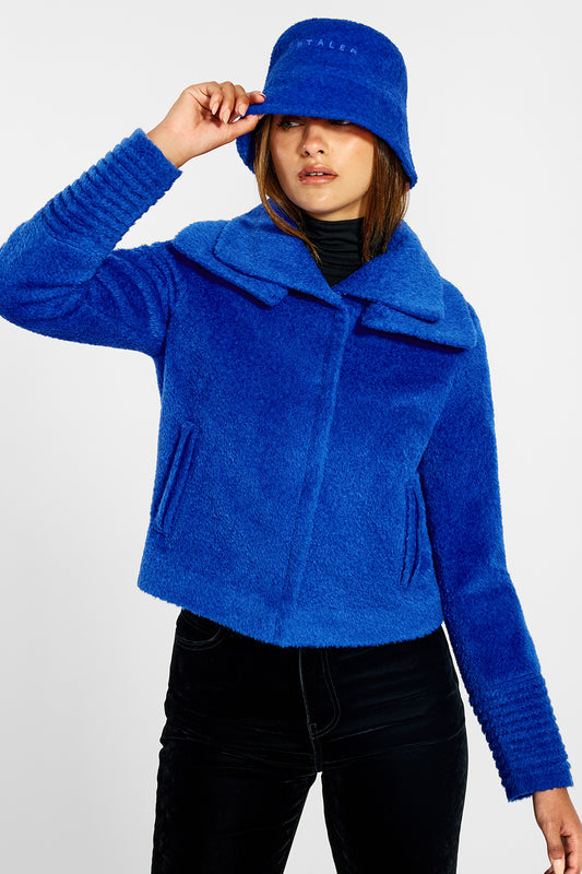 Sentaler Bouclé Alpaca Moto Jacket with Signature Double Collar and the Bouclé Alpaca Bucket Hat crafted in Bouclé Alpaca and in Cobalt Blue. Seen from front above the knees on female model.