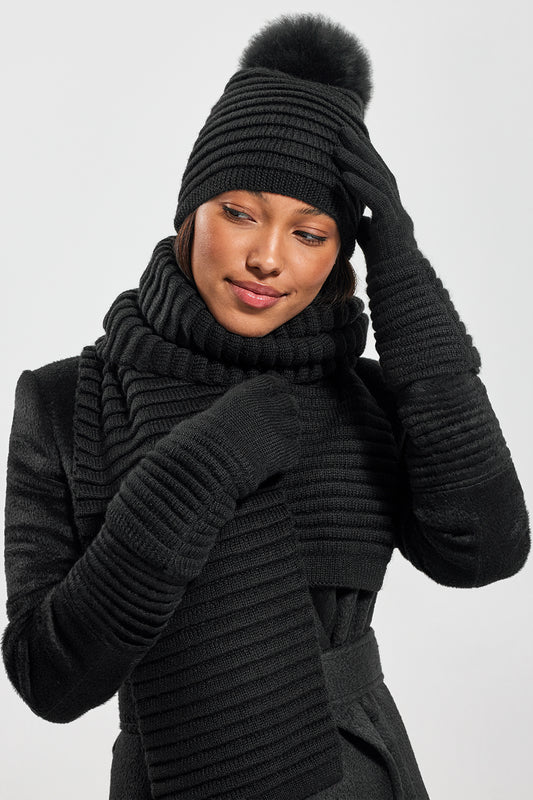 Sentaler Adult Ribbed Hat With Oversized Fur Pompon, Adult Ribbed Scarf and Adult Ribbed Gloves featured in Baby Alpaca and available in Black. Seen from front on model.