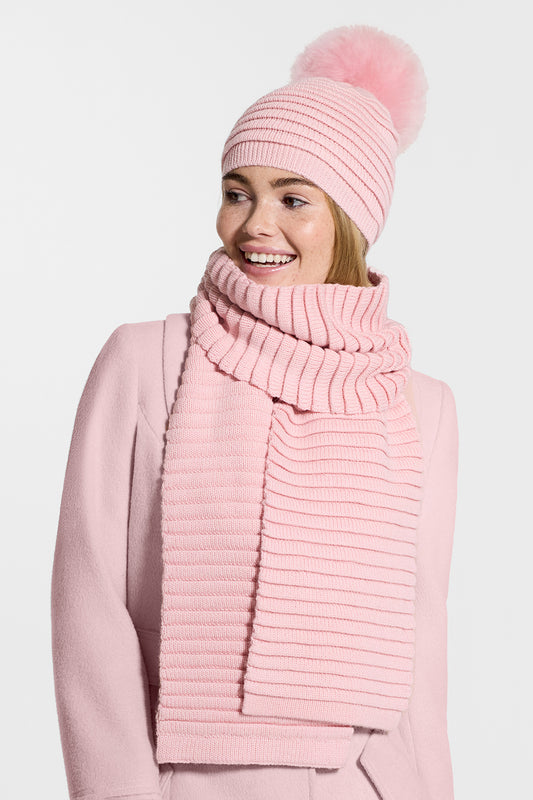 Sentaler Kids (1-5 Years) Ribbed Hat with Oversized Fur Pompon and Ribbed Scarf featured in Baby Alpaca and available in Pink. Seen from side above the waist on model.