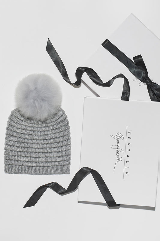 Sentaler Adult Ribbed Hat With Oversized Fur Pompon featured in Baby Alpaca and available in Grey. Seen as Holiday Flat Lay.