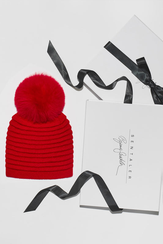 Sentaler Adult Ribbed Hat With Oversized Fur Pompon featured in Baby Alpaca and available in Red. Seen as Holiday Flat Lay.