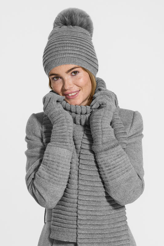 Sentaler Adult Ribbed Scarf, Ribbed Hat with Oversized Fur Pompon, Ribbed Gloves featured in Baby Alpaca and available in Grey. Seen from front above the waist on model.