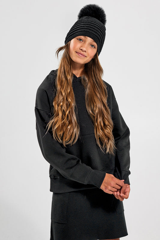 Sentaler Kids (6-14 Years) Ribbed Hat with Oversized Fur Pompon featured in Baby Alpaca and available in Black. Seen from front above the knees on model.