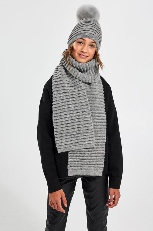 Sentaler Kids (6-14 Years) Ribbed Hat with Oversized Fur Pompon featured in Baby Alpaca and available in Grey. Seen from front on model above the knees with Ribbed Scarf in Grey.