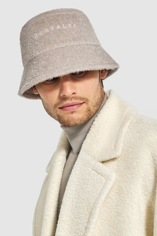 Sentaler Mens Bouclé Alpaca Bucket Hat featured in Bouclé Alpaca and available in Sand. Seen from front close up on model.